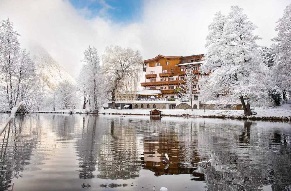 Blick vom See auf den Tramser Hof in verschneiter Winterlandschaft