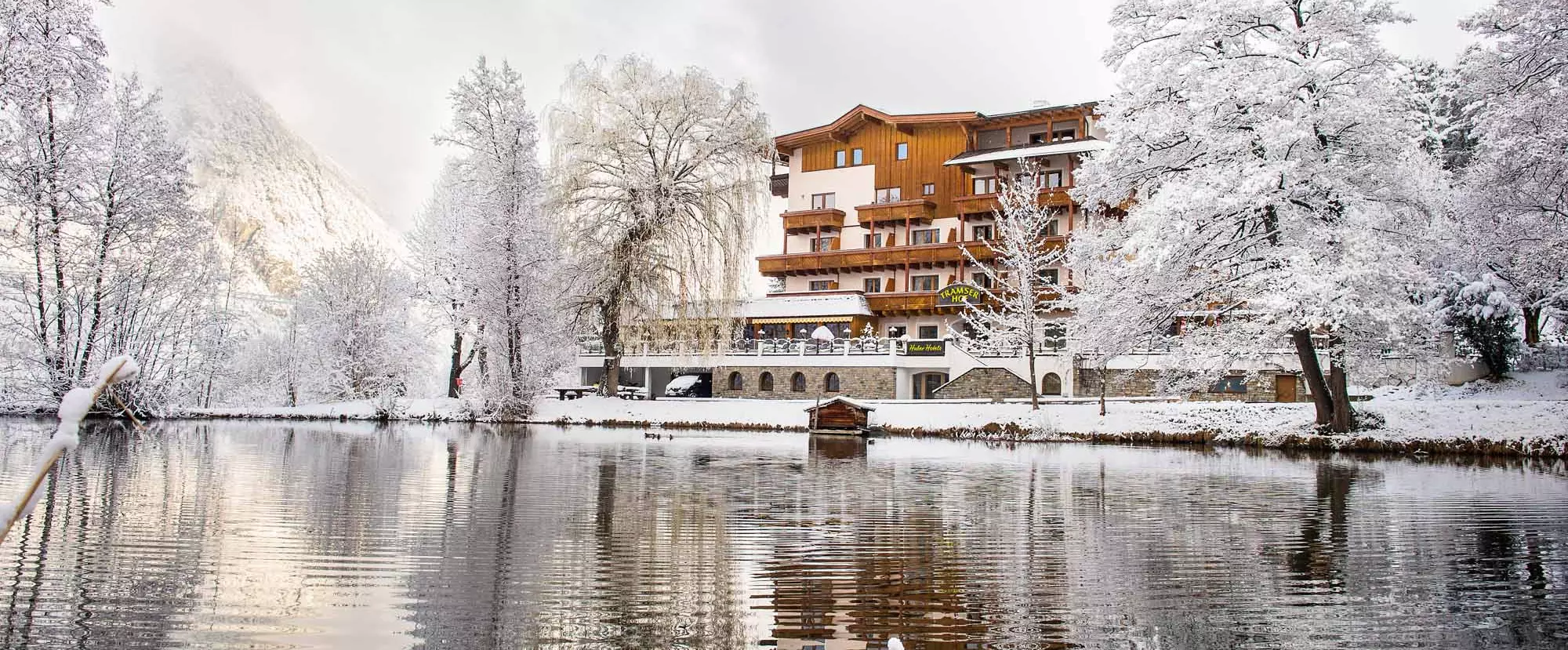 Blick vom See auf den Tramser Hof in verschneiter Winterlandschaft