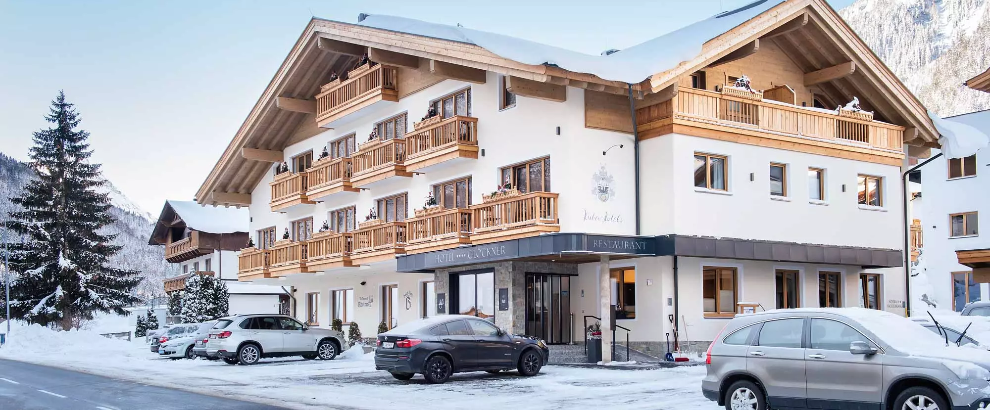 Fassade und Parkplatz des Hotel Glöckner im Winter bei Neuschnee und Sonnenschein